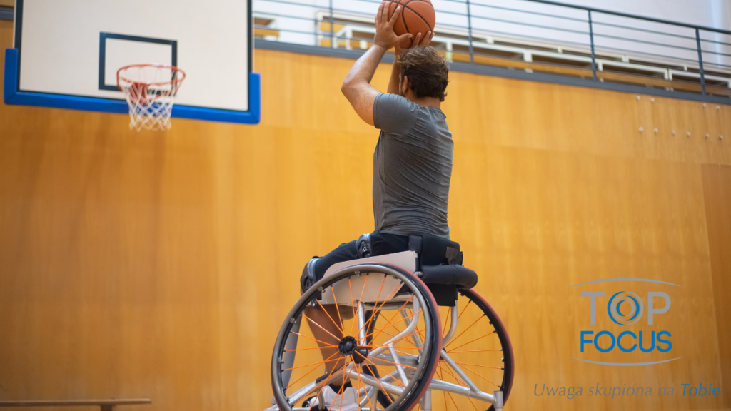 Mężczyzna na wózku inwalidzkim gra w koszykówkę na hali sportowej.